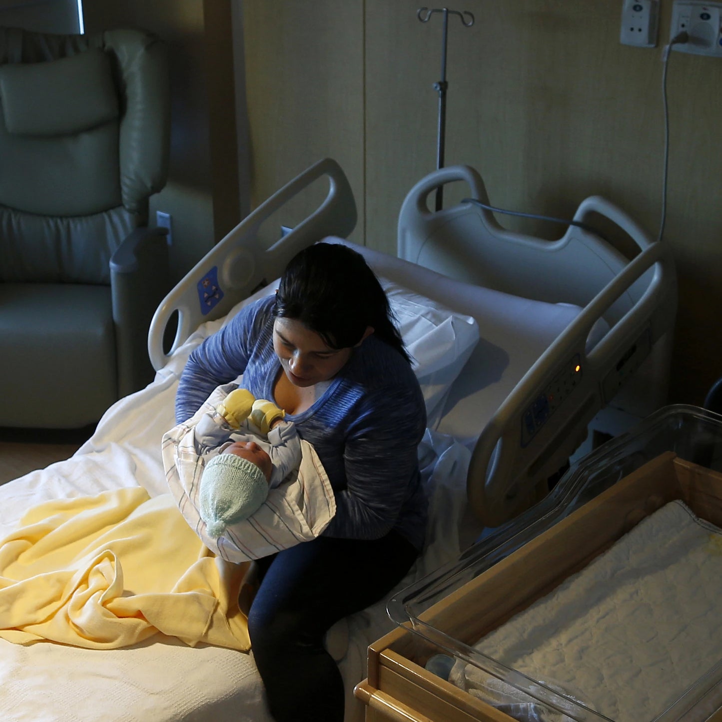 Mother sitting on hospital bed with infant.